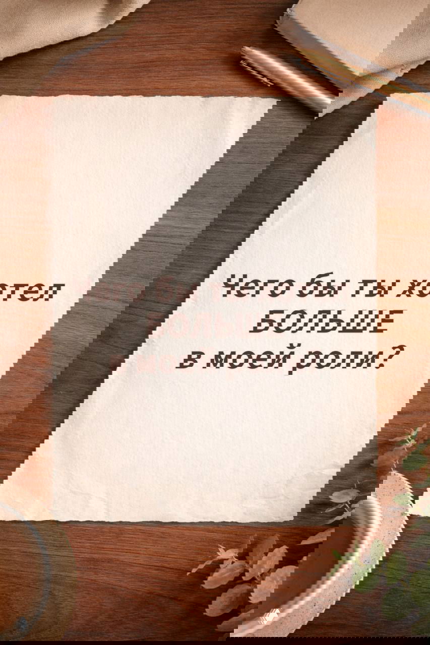 Лист бумаги с текстом «Чего бы ты хотел БОЛЬШЕ в моей роли?», минималистичная композиция с ручкой и растением на столе.