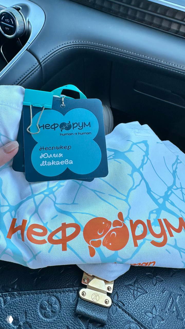 Бейдж участника НеФорума с именем Юлия Макаева и фирменный мерч в салоне машины: детали поездки и организационный штрих съёмки.