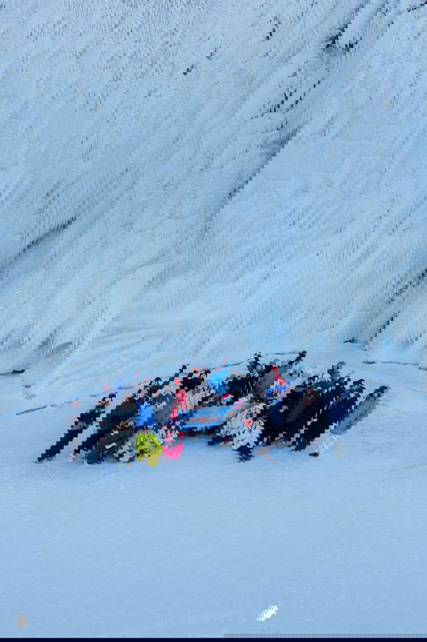 Большая группа участников на фоне гигантских ледяных занавесов и скал: общая фотография у впечатляющих ледяных образований на Байкале.