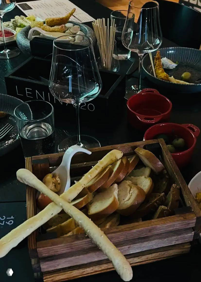 Корзина с хлебом и хлебными палочками на столе дегустации, рядом бокалы и закуски — атмосферный вид стола во время вина.