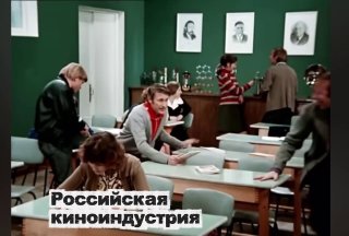 Кадр фильма: люди в учебной аудитории за столами, на заднем плане реквизит съёмочной сцены; внизу белая подпись «Российская киноиндустрия».