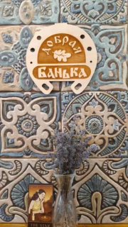 Декоративная плитка и деревянная вывеска «Добрая Банька», ваза с сухой лавандой и иллюстративная карточка — уютная атмосфера банного ретрита.