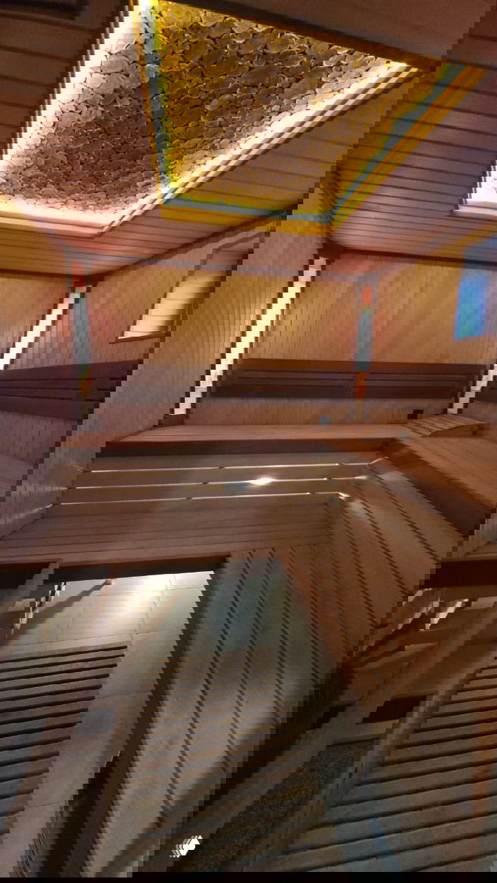 Внутренний вид парной: деревянные скамьи и полки, тёплый свет в потолочной нише и уютная атмосфера традиционной сауны для релаксации.