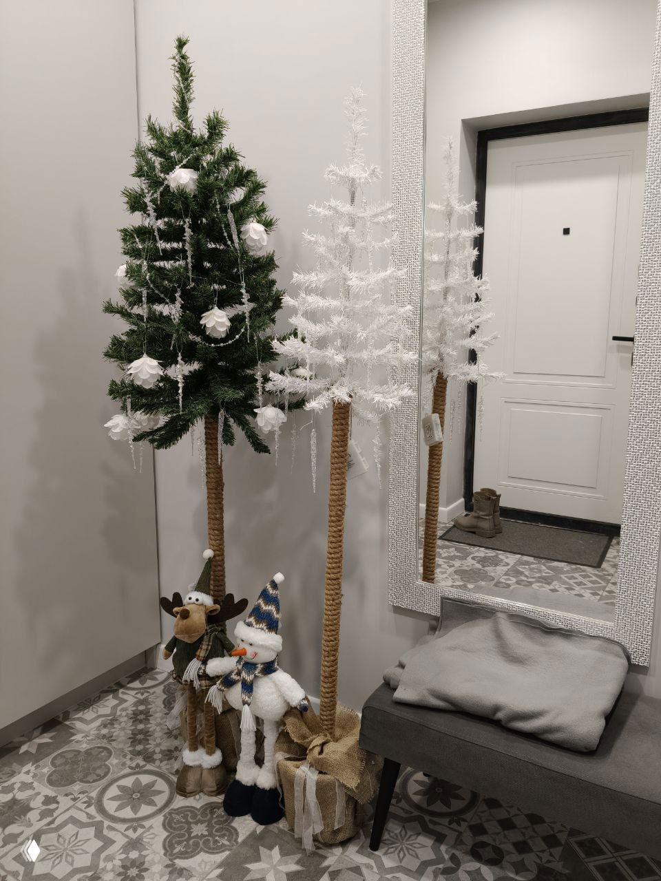 Прихожая с декоративными мини-ёлками, большим зеркалом и уютной скамьёй у входа — оформление пространства для гостей банного дома.