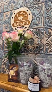 Настенная плитка с табличкой «Добрая Банька», букет роз, карта Таро «The Star», кристаллы и свечи на столе — декоративная композиция для банного мероприятия.