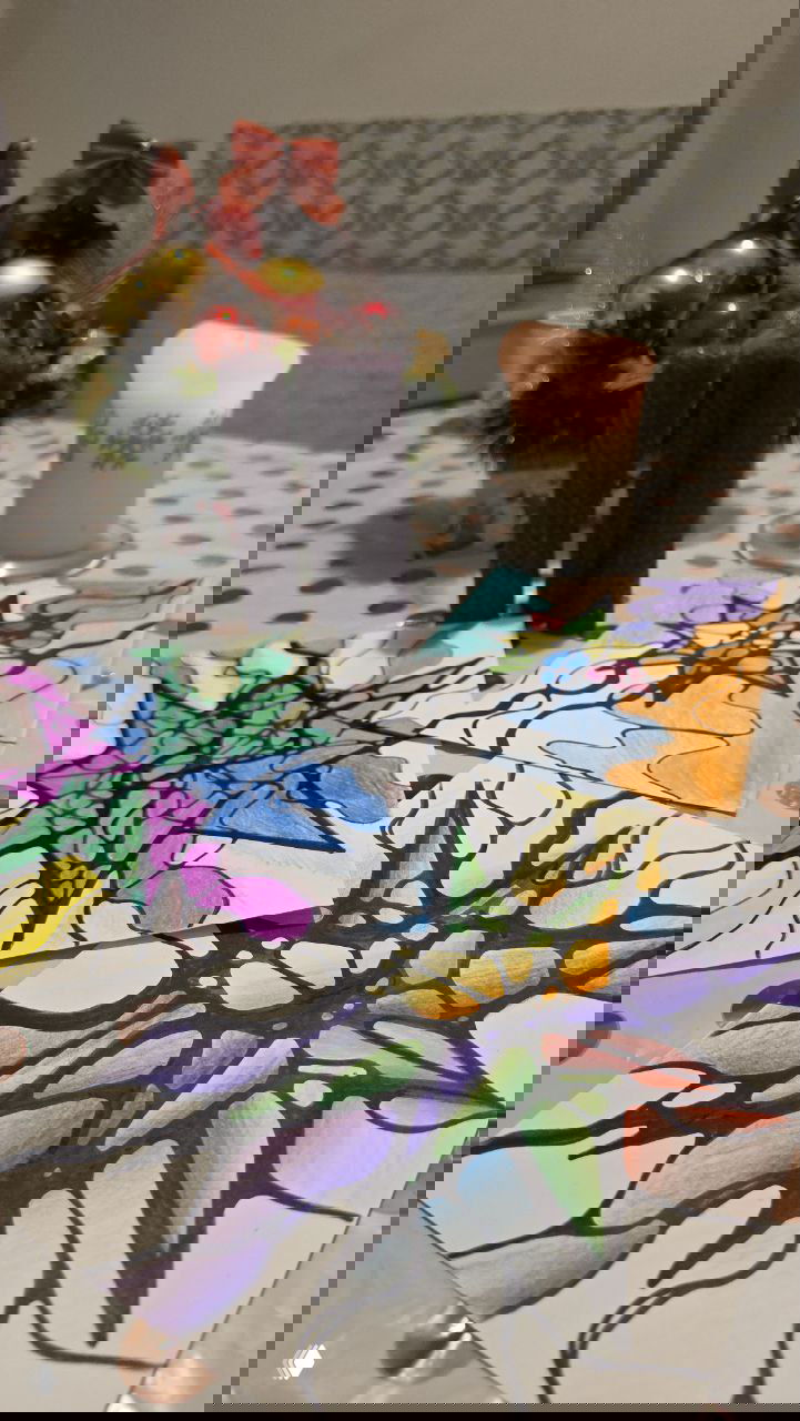 Набор нейрографических рисунков на столе рядом с двумя фиолетовыми свечами и одной декоративной свечой; на фоне виден праздничный декор.