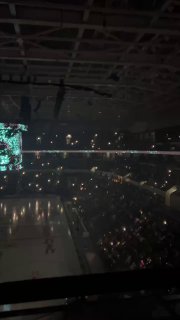 Темное фото арены во время ледового шоу: ледовая площадь, сценическая подсветка и множество зрителей с фонариками создают атмосферу представления.