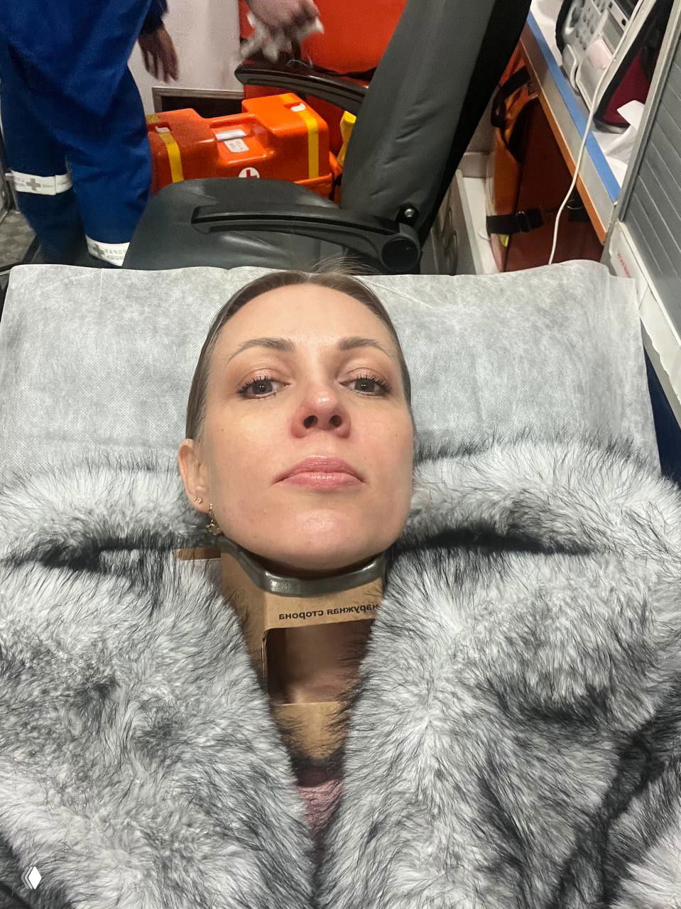 Женщина лежит на носилках в машине скорой помощи с шейным воротником (воротником Шанца), рядом видна медицинская аппаратура и сумка медиков.