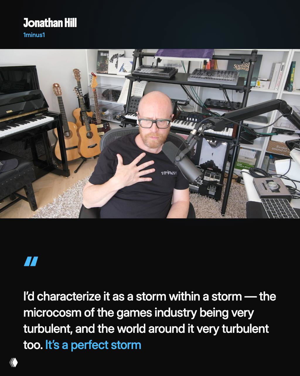 Jonathan Hill sitting in a home studio surrounded by guitars, keyboards and microphones, addressing camera in an interview frame for the documentary.
