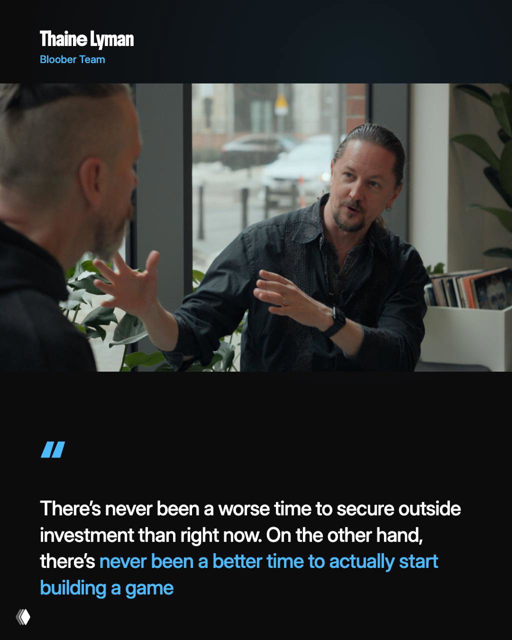 Thaine Lyman in a candid café-style conversation, gesturing with hands while discussing investment timing and the opportunity to start building games now.