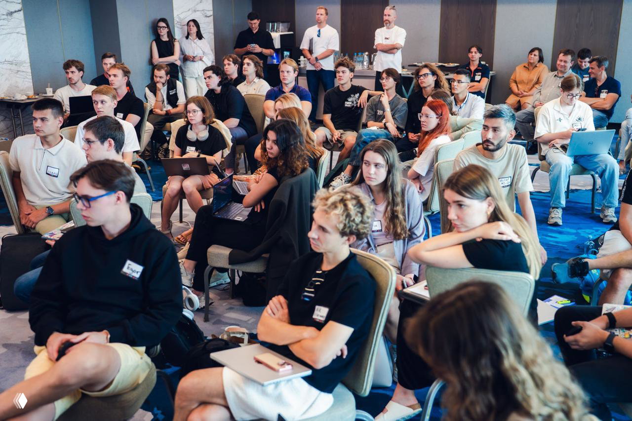 Group of hackathon participants seated with laptops and notebooks, listening attentively to mentors and sessions during the one-day event.