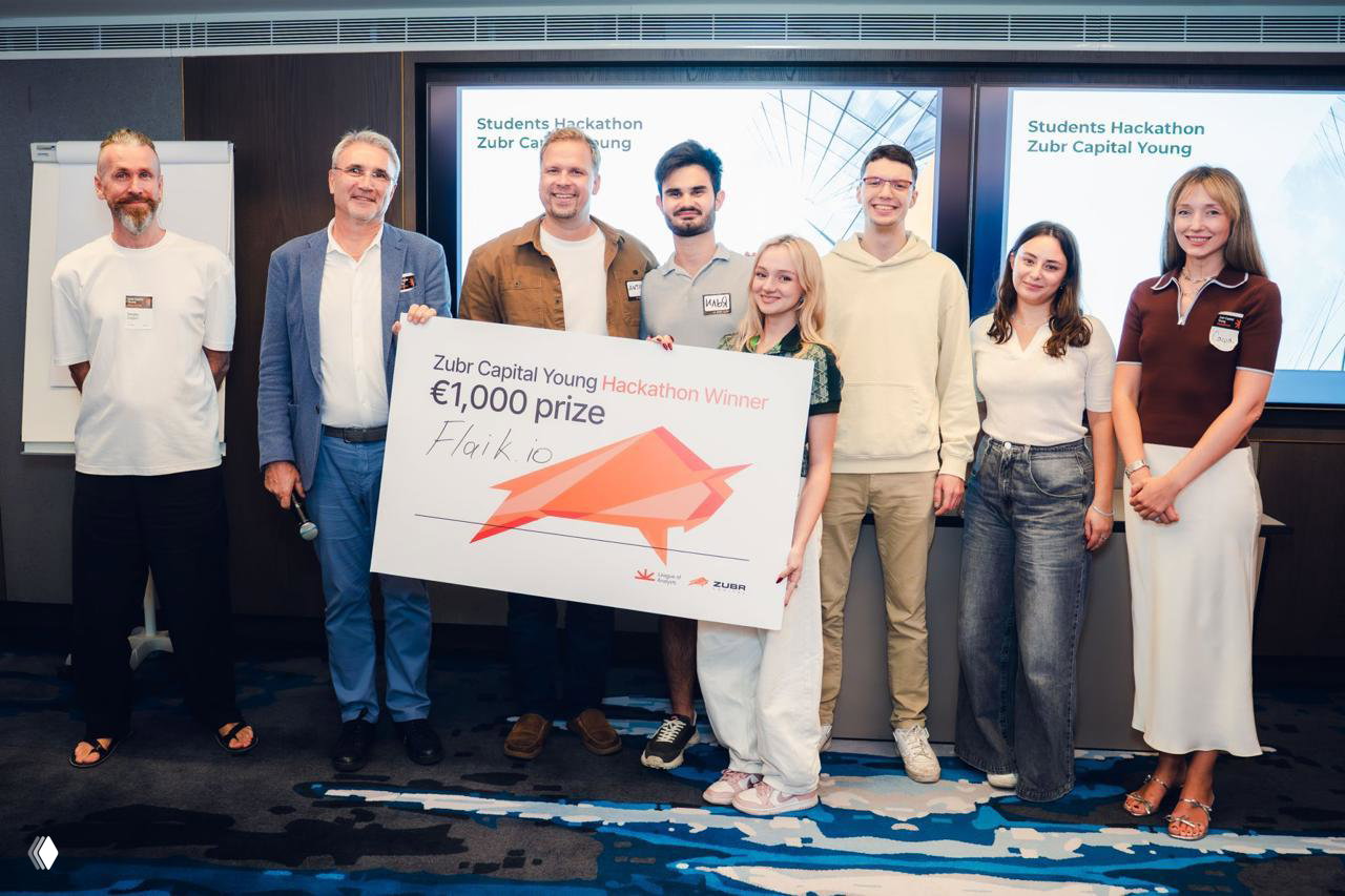 Winners on stage holding a large cheque for €1,000 at the Zubr Capital Young Hackathon award ceremony, team and organizers posing together.