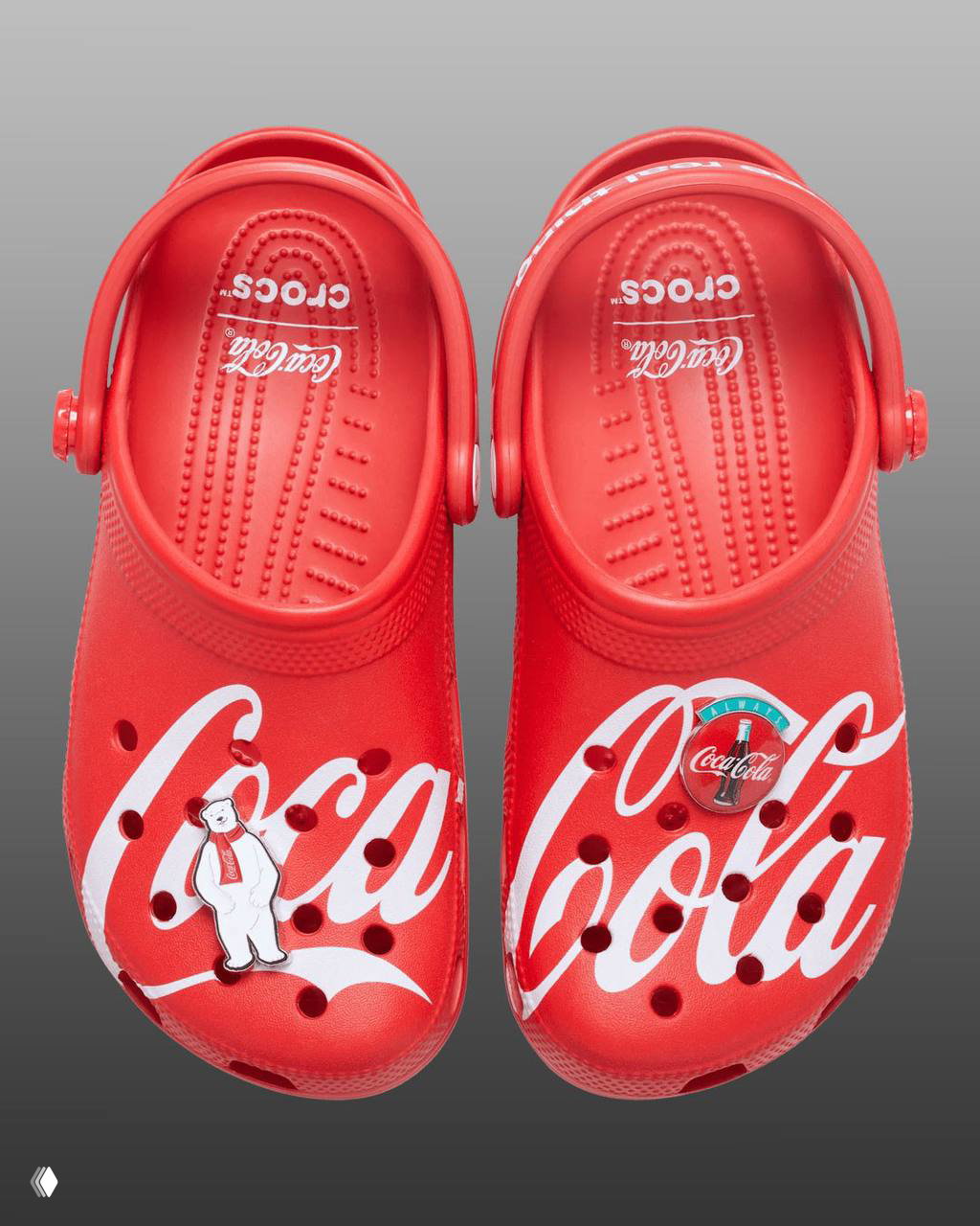 Вид сзади красных клоггов Coca‑Cola: на ремешках надпись "it's the real thing." и форма подошвы, студийная съёмка на градиентном фоне.