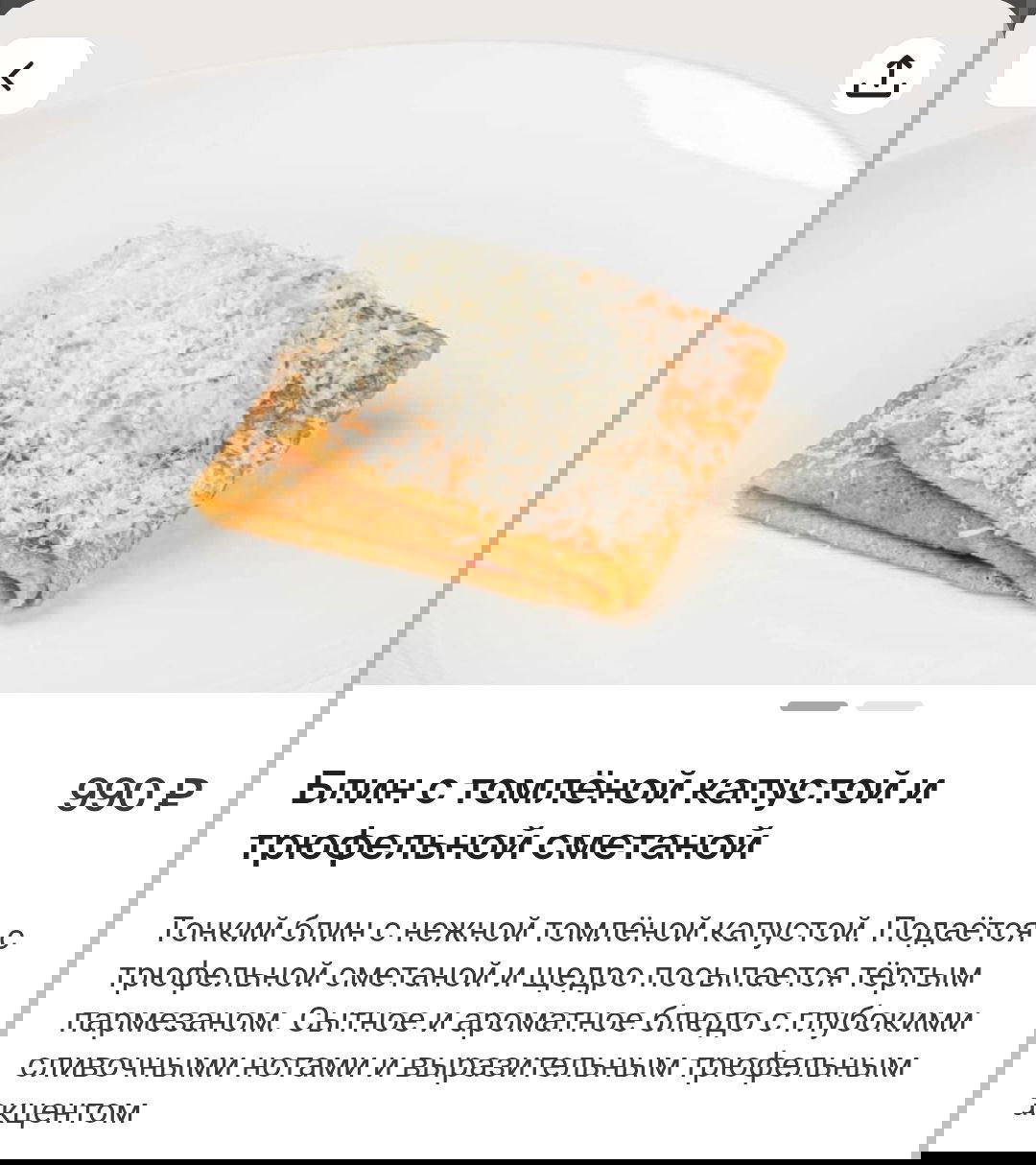 Блин с томлёной капустой и трюфельной сметаной, посыпанный тёртым пармезаном на белой тарелке — фото из меню Кофемании.