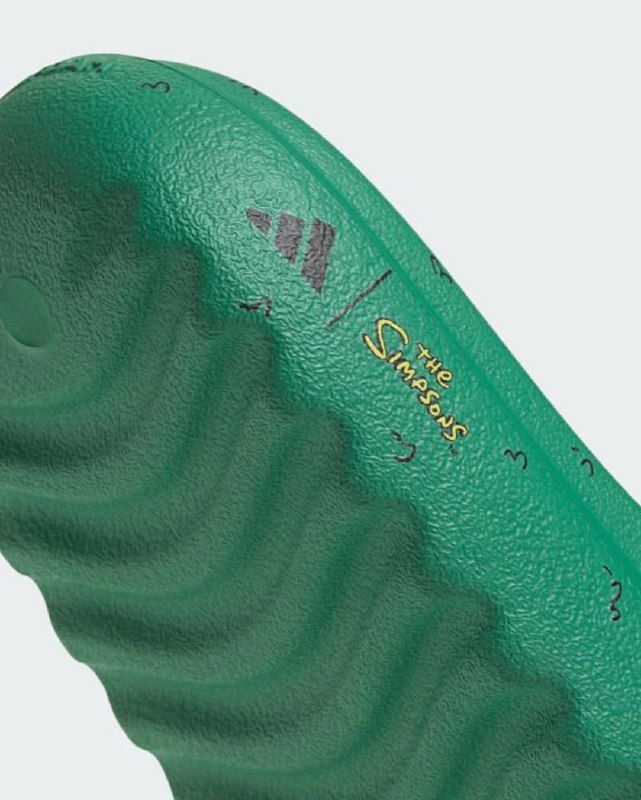 Детальный вид подошвы и текстуры зеленых тапочек Adilette, фрагмент рисунка и элементы дизайна коллаборации The Simpsons с adidas.