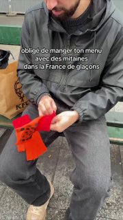 Уличный кадр из превью: мужчина сидит и взаимодействует с оранжевыми перчатками с принтом, на экране видны французские субтитры и городской фон.