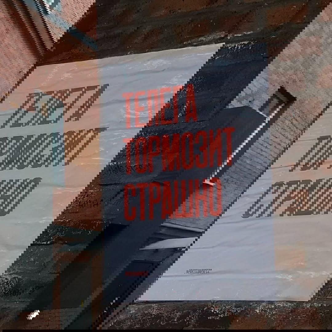 Плакат, приклеенный к кирпичной стене в городской среде Москвы: белый фон и крупная красная надпись «ТЕЛЕГА ТОРМОЗИТ СТРАШНО».