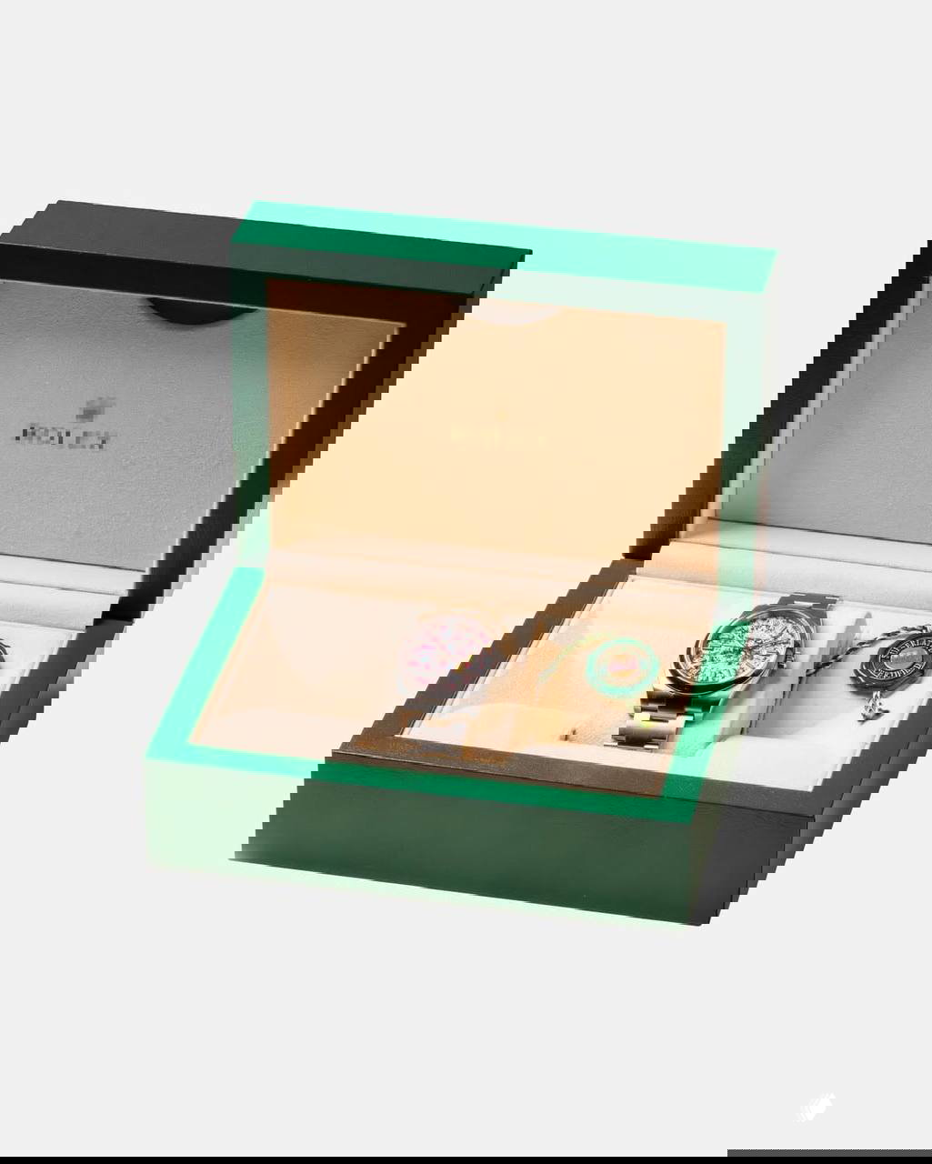 Роскошный зелёный футляр Rolex открыт, внутри лежат часы с ярким, многокрасочным циферблатом — композиция арт‑предмета перед фотографированием для каталога.