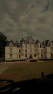 Кадр из промо‑ролика: большой особняк или шато на фоне пасмурного неба, возможная локация съёмок кампейна Bero и Aston Martin.