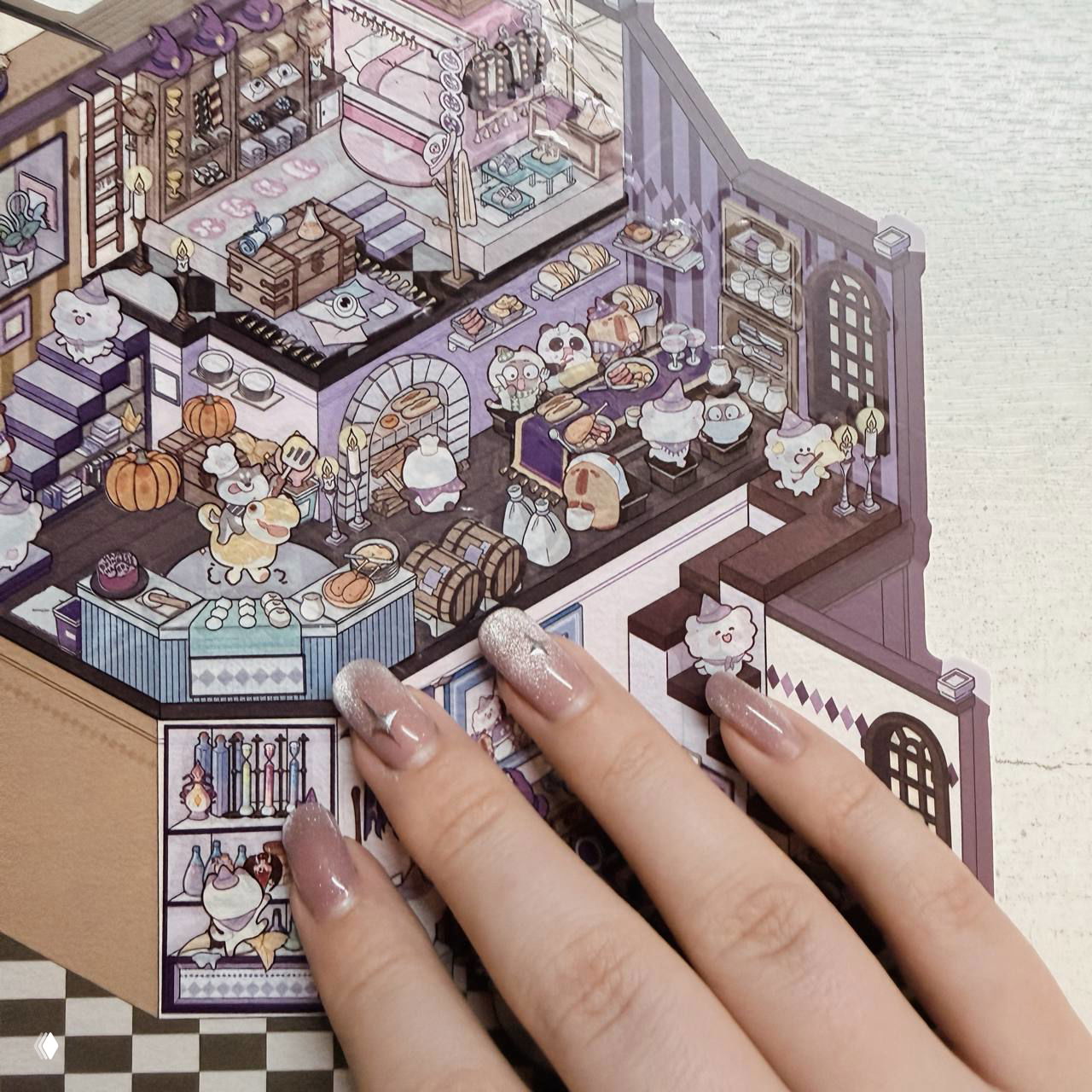 Изометрическая сцена румбокса с миниатюрной кухней в фиолетовых тонах; рука с аккуратным маникюром касается модели.