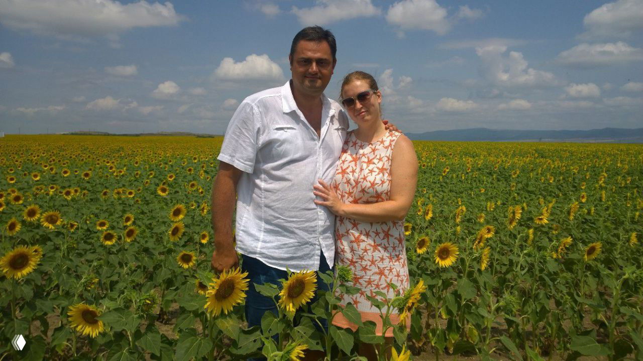 Пара на фоне поля подсолнухов в Болгарии: летний пейзаж, солнце и широкое поле с цветущими подсолнухами, туристическая фотография.