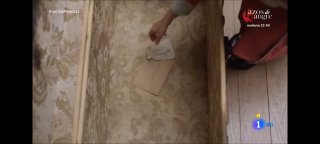 Рука опускает конверт в ящик комода на фоне деревянного пола и мебели; кадр передаёт ощущение ностальгии, тайны и утраты.