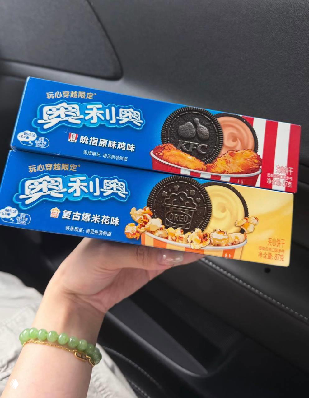 Человек держит две пачки лимитированных Oreo x KFC в машине: видны упаковка с KFC, рисунки печенья и акцент на попкорне и курице.