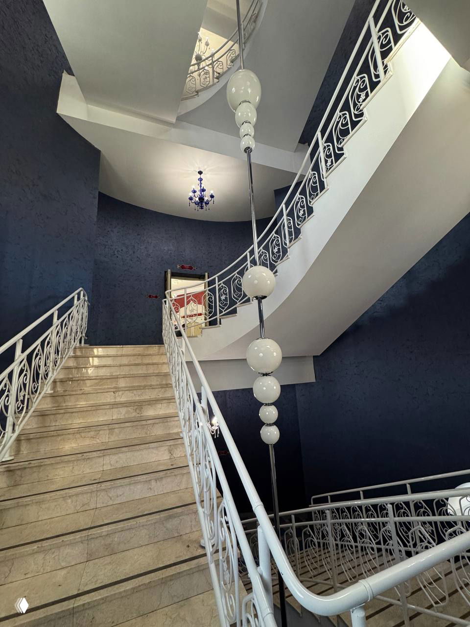 Внутренний вид лестничного пролёта с белыми перилами и подвесными шарообразными светильниками, архитектурные формы подчеркивают сказочный образ театра.