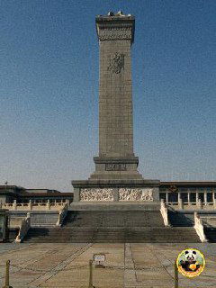 Высокий монумент на большой площади, массивная колонна и широкая открытая плоскость перед ним, символическая городская точка ориентира.