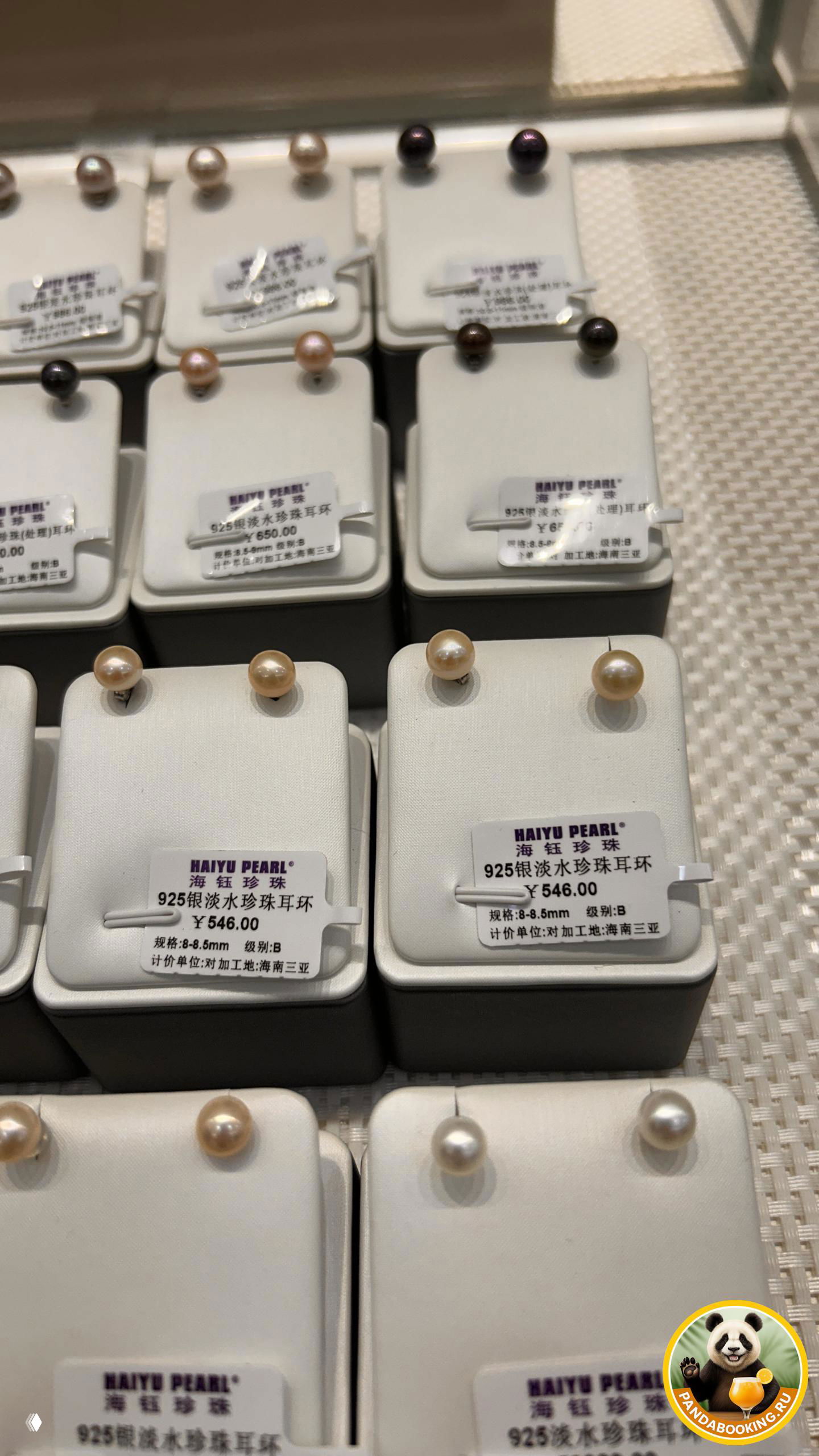 Снимок центральной части прилавка с рядами пар жемчужных серёжек, в том числе классических каплевидных и круглых моделей с ценниками в юанях.
