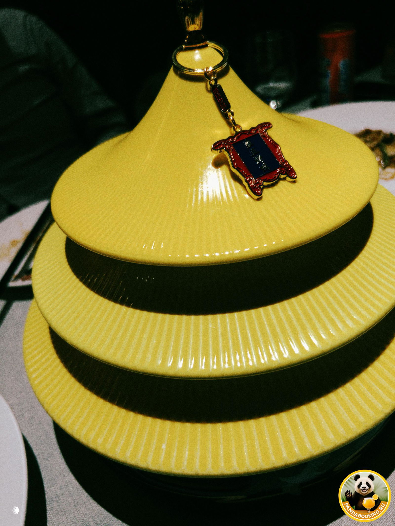 Накрытые стопкой жёлтые блюдца с декоративным брелоком сверху — оригинальная посуда для подачи блюд в ресторане Пекина.