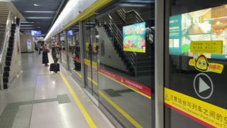 Платформа метро Гуанчжоу с защитными раздвижными дверями и стоящим поездом; видно табло и порядок на станции.