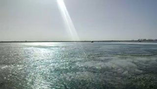 Широкий вид реки Маныч у Степного Кургана в конце февраля: тонкий лед, блики солнца на поверхности и удалённый горизонт.