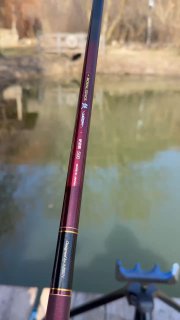 Крупный план махового удилища Royal Stage, видна часть лески и спокойная поверхность пруда на фоне