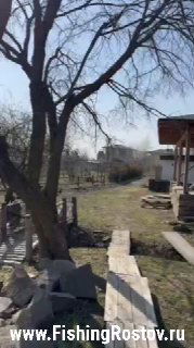 Просека и дорожка у форелевого пруда, деревянные настилы и постройки на заднем плане, вид весеннего участка с голыми деревьями