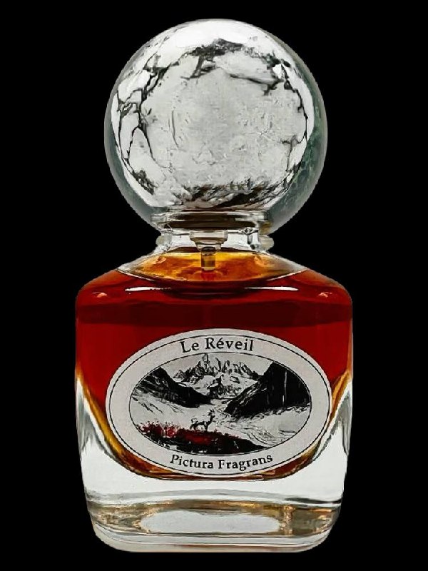 Крупный план флакона Pictura Fragrans «Le Réveil»: насыщенно-тёмная янтарная жидкость, стеклянная шарообразная крышка и овальная этикетка.