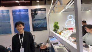 Выставочный стенд бренда с улыбчивым мужчиной рядом с витриной духов и флаконами, демонстрация упаковки и концепта бренда Cottee на фоне экспозиции.