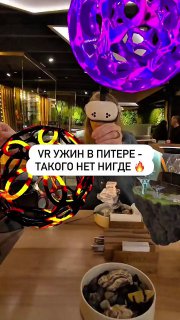 Интерьер ресторана с AR‑инсталляциями: фиолетовые светящиеся объекты над столами, тарелки с закусками и наклейка «VR УЖИН В ПИТЕРЕ» на кадре.