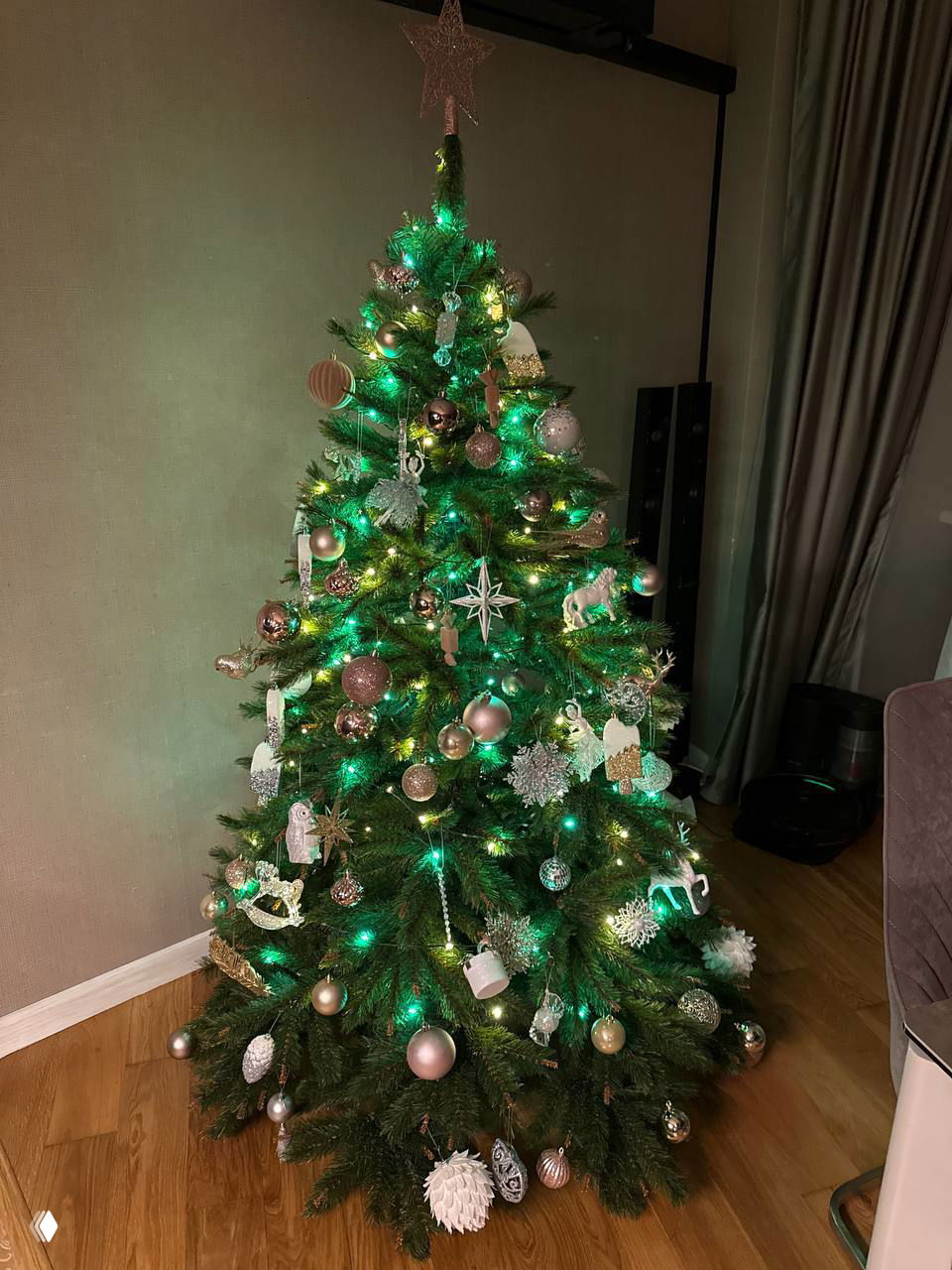 Украшенная живая ёлка в домашнем интерьере с мерцающими гирляндами и шарами — праздничный декор перед Новым годом.