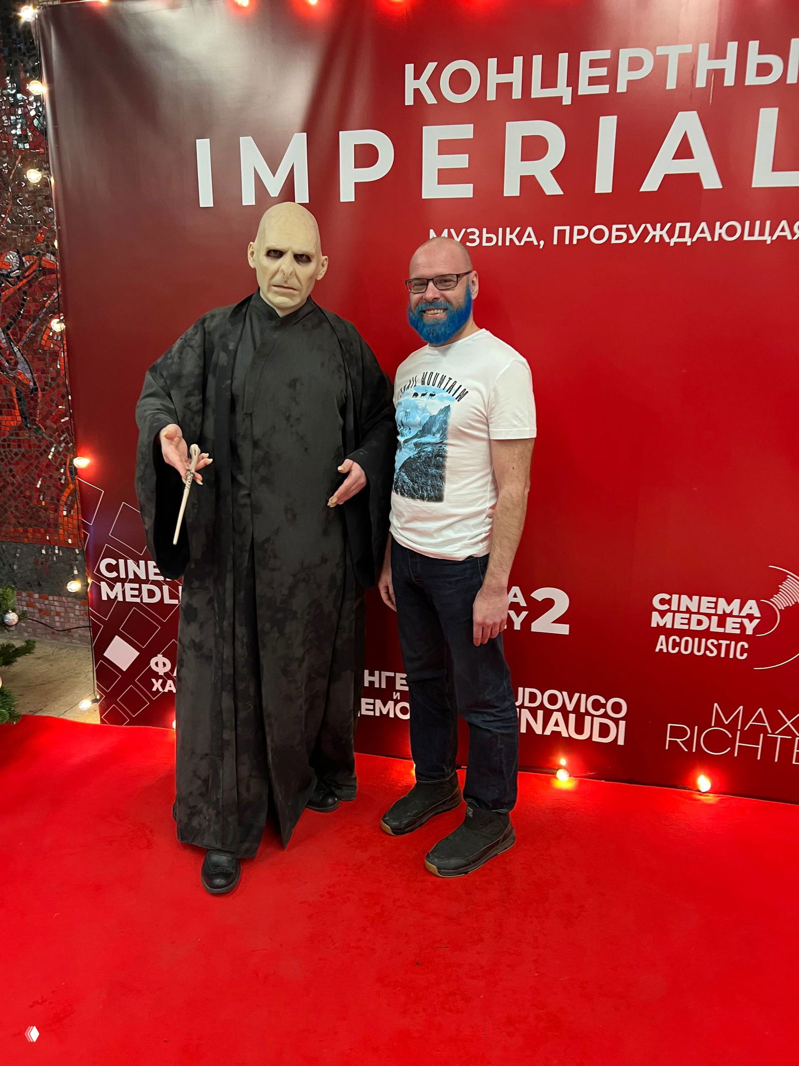 Воландеморт и посетитель позируют на красной дорожке у баннера «IMPERIAL»; реквизит и оформление фотозоны видны крупно.