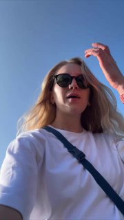 Автор в белой бланковой футболке и солнцезащитных очках на фоне чистого голубого неба, крупный план с акцентом на материал и посадку