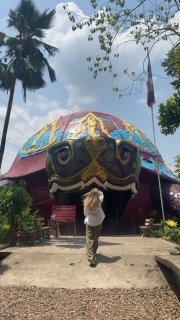 Купол здания в форме большой черепахи с синими и золотыми орнаментами, посетитель идёт к входу; пальмы и открытое пространство вокруг. Фото автора.