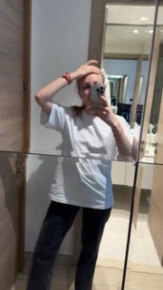 Селфи в зеркале гостиничного номера: девушка в белой футболке и тёмных леггинсах держит телефон, показывает повседневный travel‑лук.