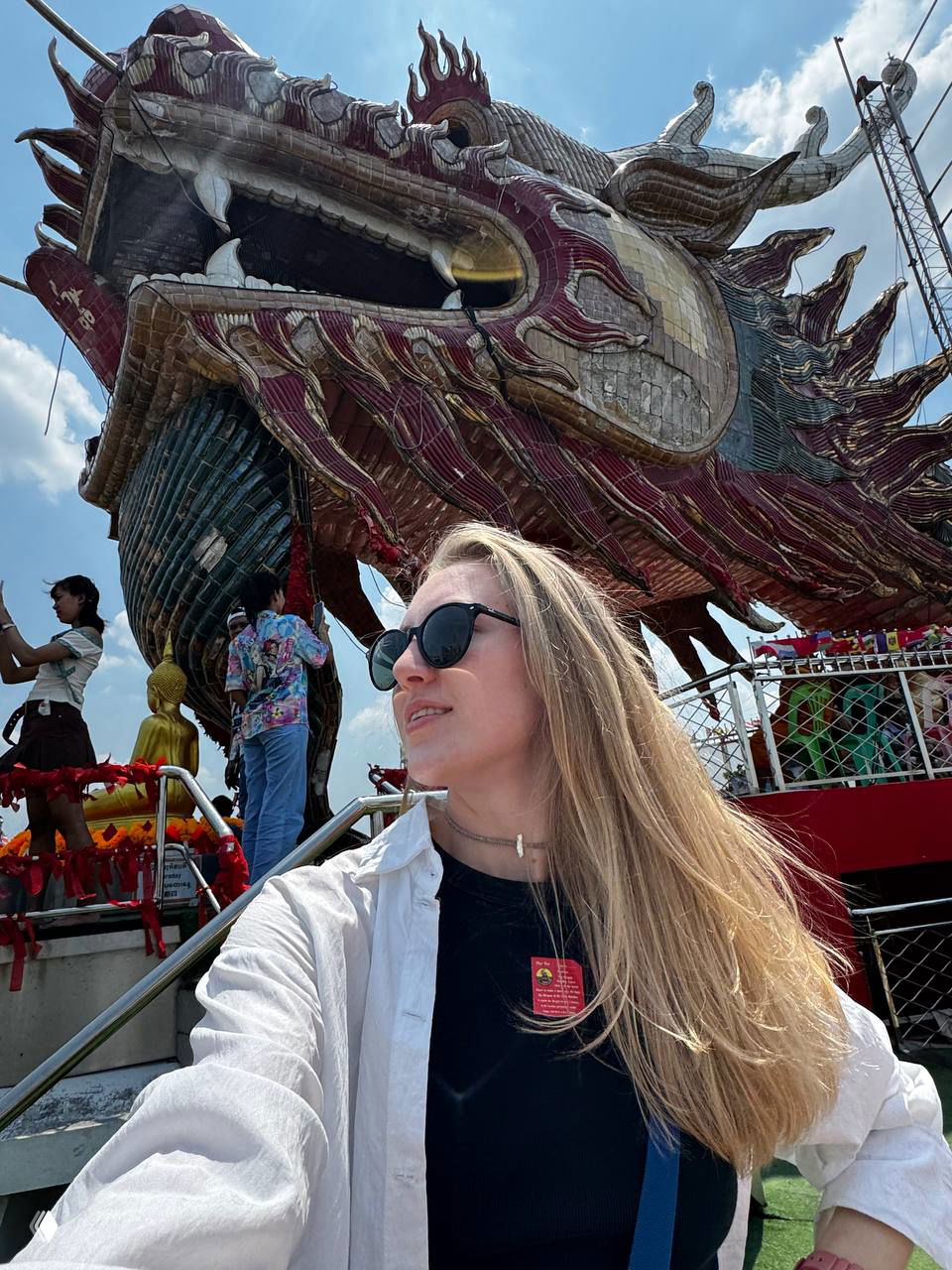 Автор на фоне большой головы дракона у входа в Ват Самфран: женщина в солнцезащитных очках, мозаичная голова дракона и туристы вокруг, солнечный день. Фото автора.