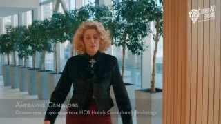 Ангелина Самадова во время интервью на форуме «ЗА ГОРИЗОНТОМ»: женщина в деловом костюме на фоне растений и светлого интерьера, логотип форума в углу.
