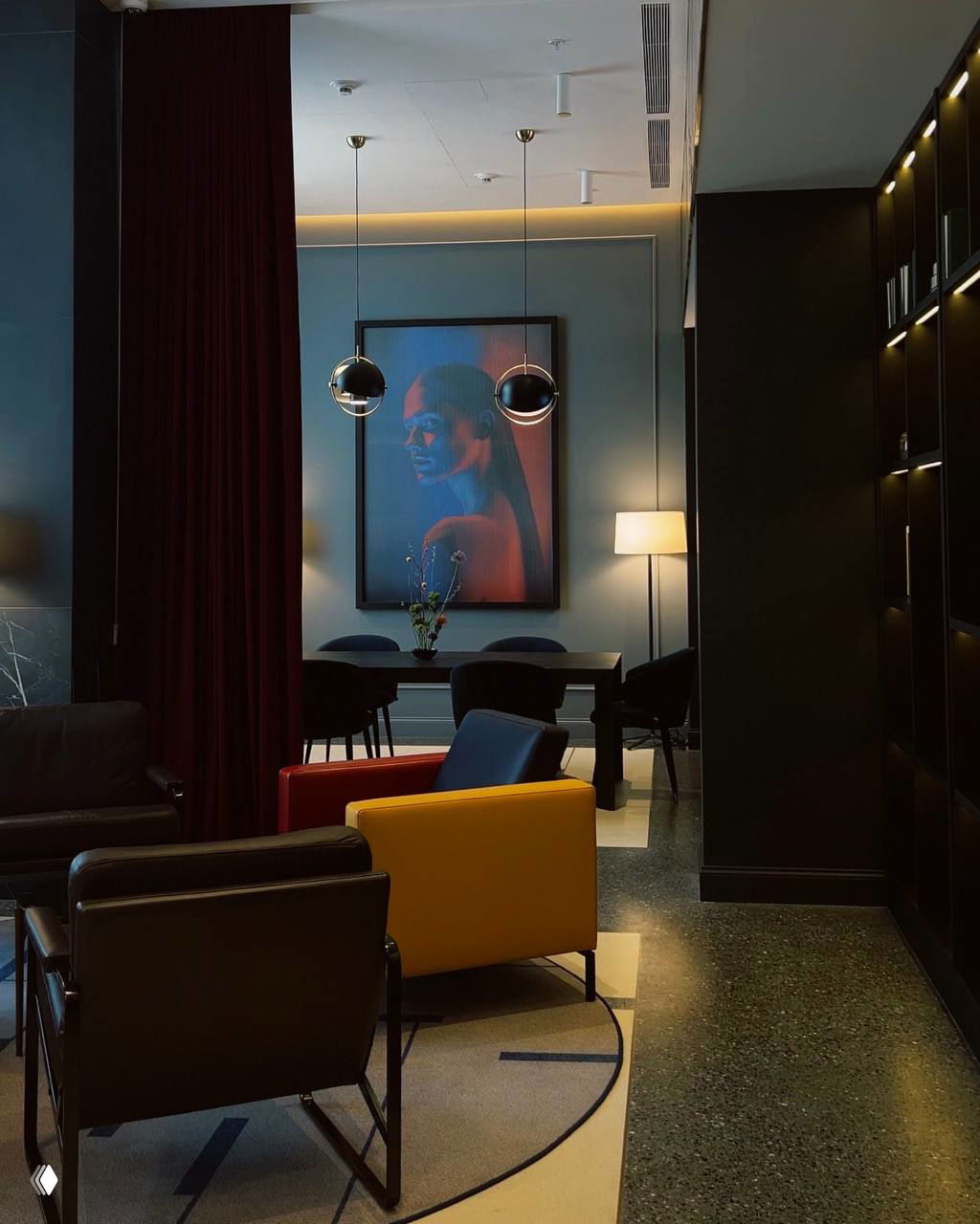 Стильная зона ожидания и лобби отеля с яркими креслами, арт‑картинами и приглушенным светом — пример общественного пространства для работы и общения.