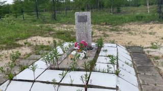 Маленькая могильная плита и оградка среди равнины — пример единичного поминального знака на заброшенной территории бывшего поселка Нефтегорск.