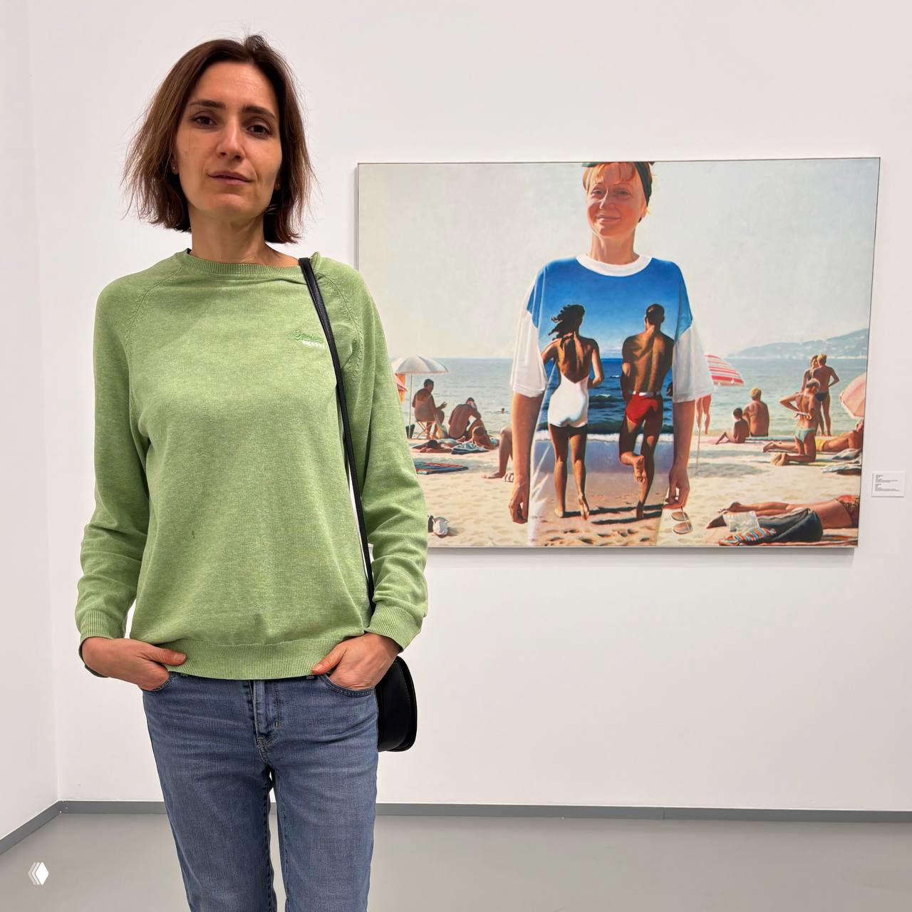 Фотография посетительницы у картины с пляжной сценой: женщина в джинсах и зелёном свитере стоит перед полотном с людьми на пляже, музейный интерьер МАММ.