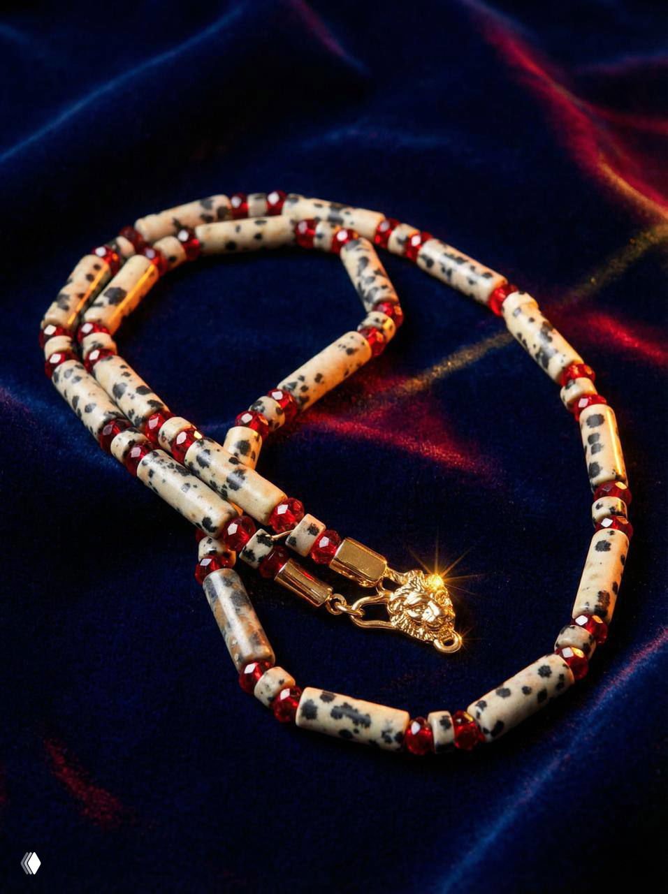 Низкоракурсный план длинных бус с цилиндрическими белыми камнями в чёрные пятна и красными стеклянными разделителями на бархатном фоне.