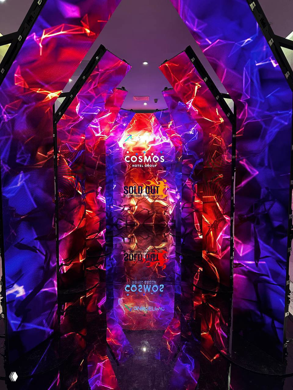 Коридор с LED-панелями, логотип COSMOS и надпись SOLD OUT в центре; яркие красно-фиолетовые узоры и отражения на глянцевом полу.